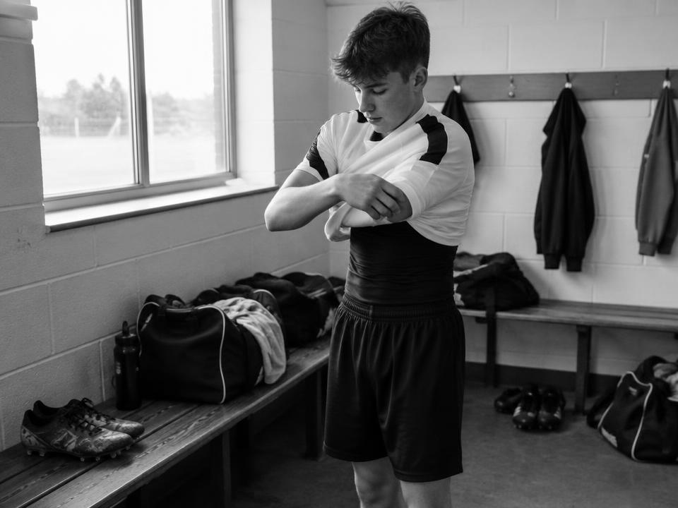 A young person pulling on a new football shirt in a club changing room